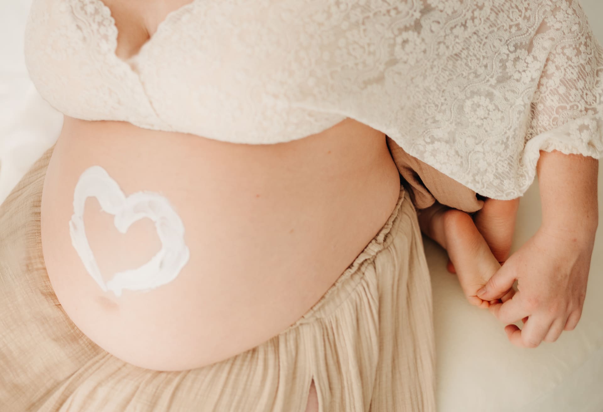 Nahaufnahme eines Babybauchs mit gemaltem Herz und kleinen Kinderhänden — Detail-Shooting Bottrop