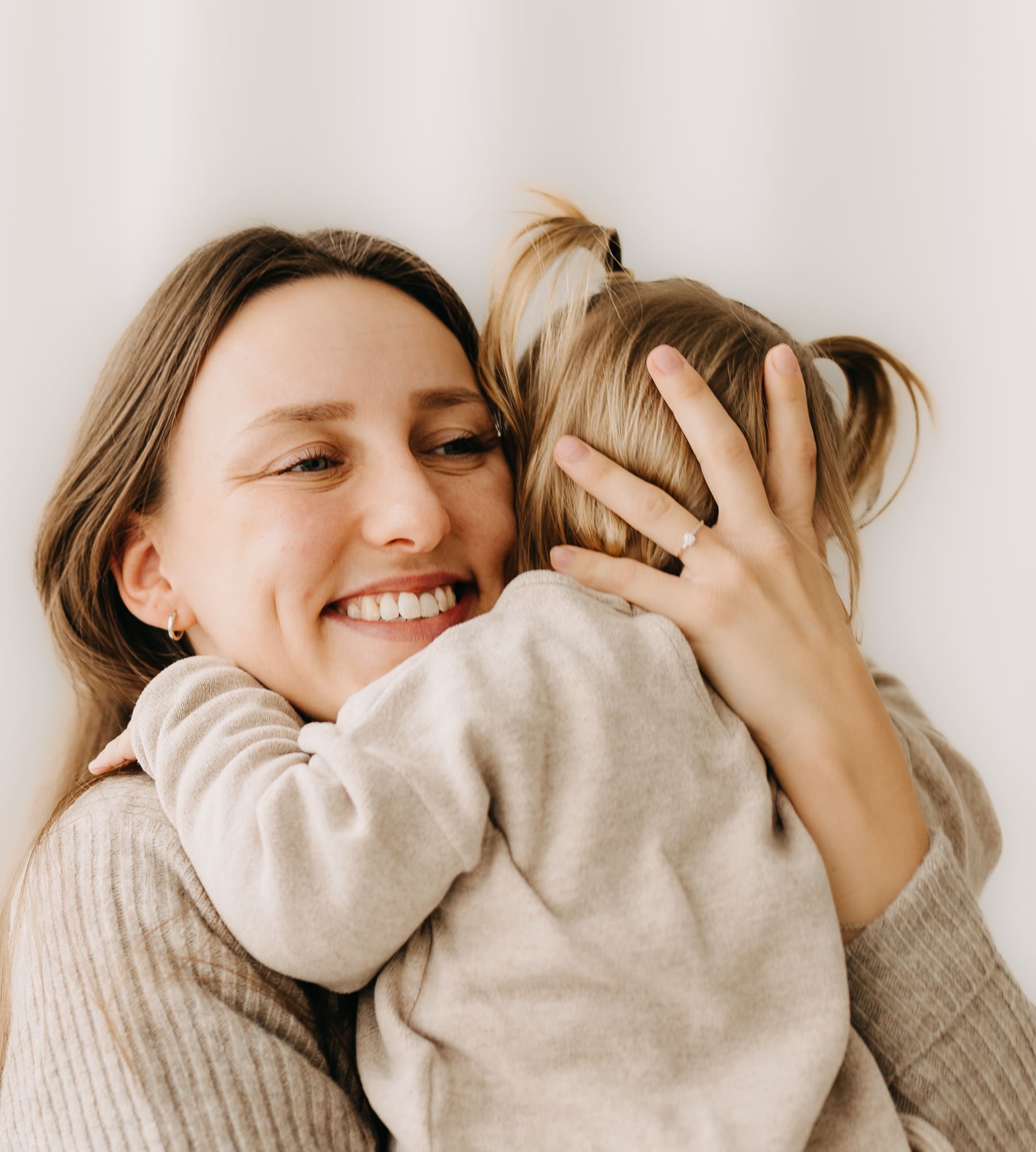 Mama hält ihr Kind im Arm und lacht — Familien-Shooting im Tageslichtstudio Bottrop