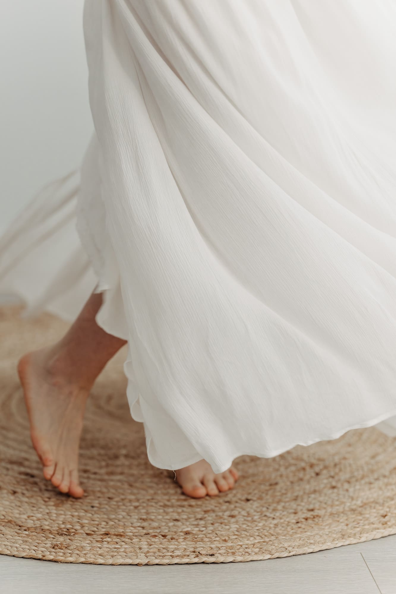 Fließendes weißes Kleid aus dem Kundenkleiderschrank — barfuß auf dem Jute-Teppich im Tageslichtstudio Bottrop