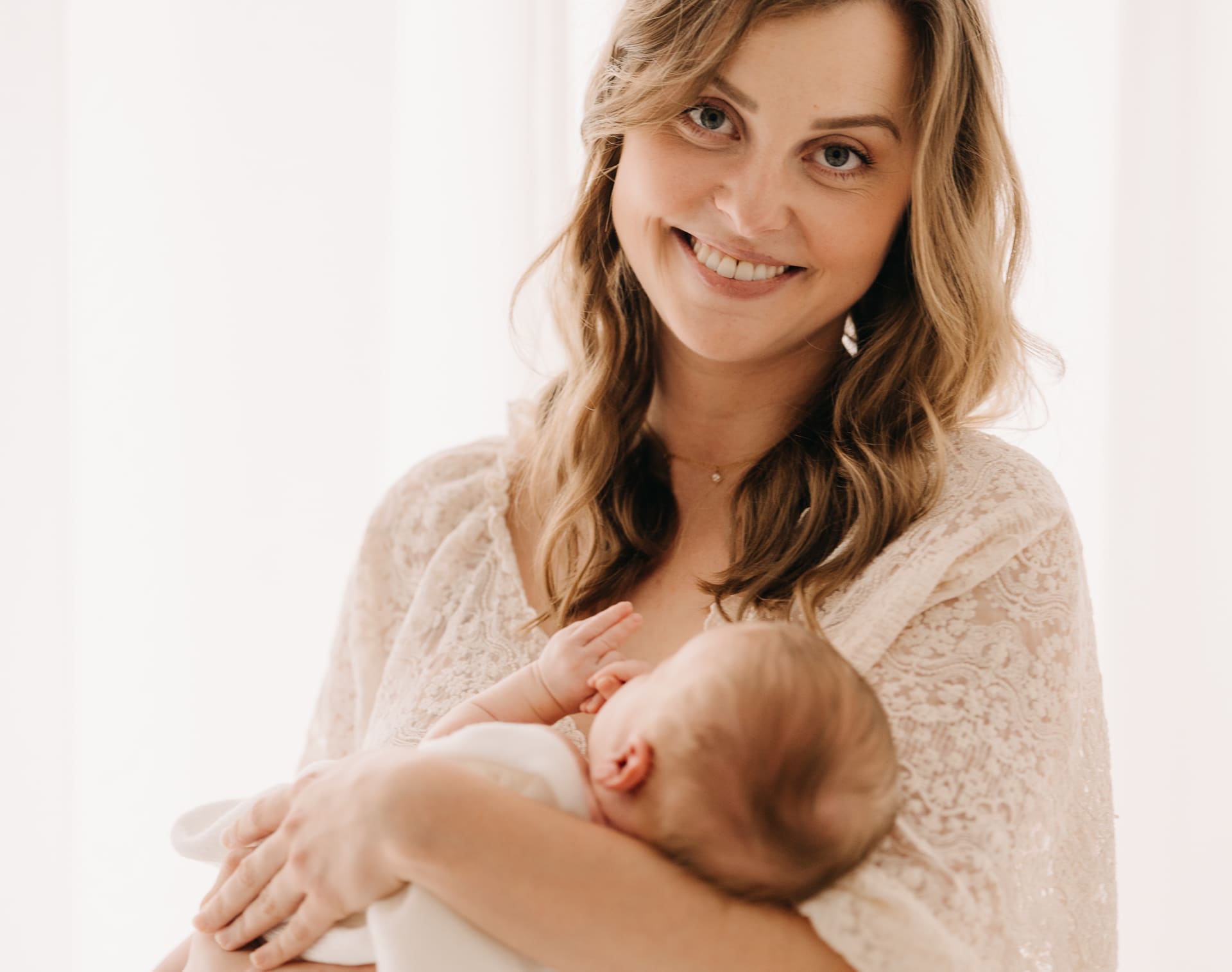 Mama hält ihr Neugeborenes im Arm und lächelt — Newborn-Shooting im Tageslichtstudio Bottrop