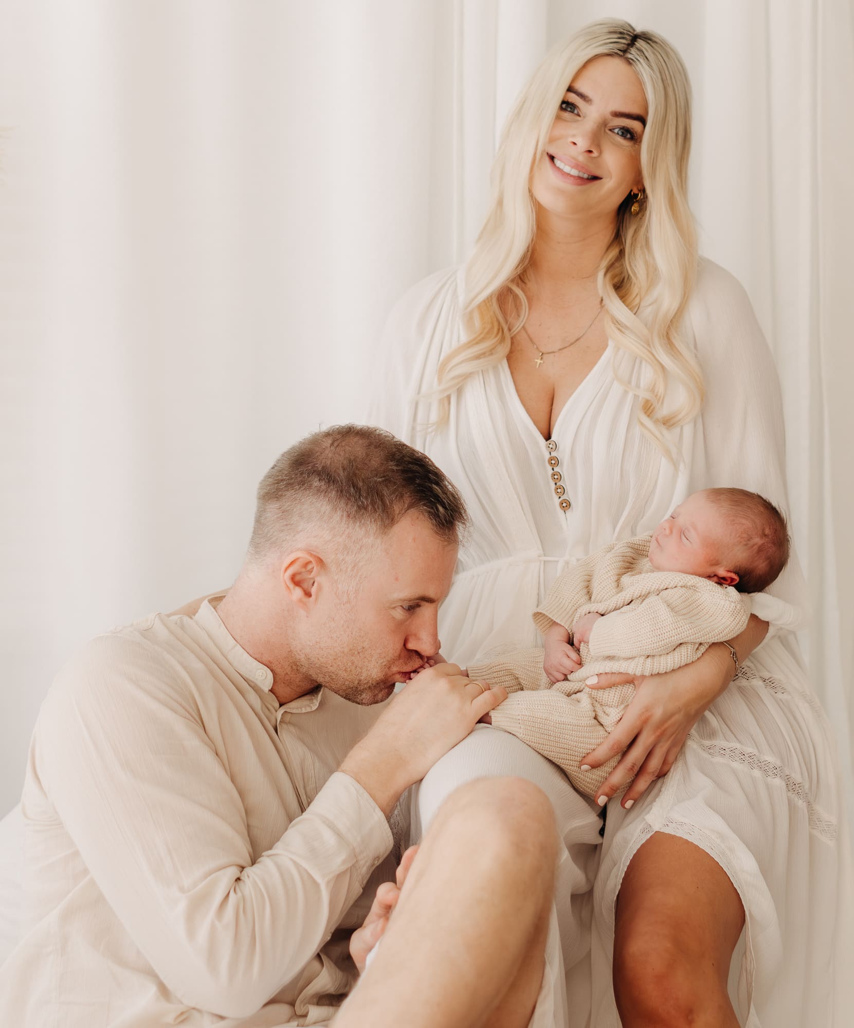 Blonde Familie hält gemeinsam ihr Neugeborenes — Newborn-Shooting im Tageslichtstudio Bottrop