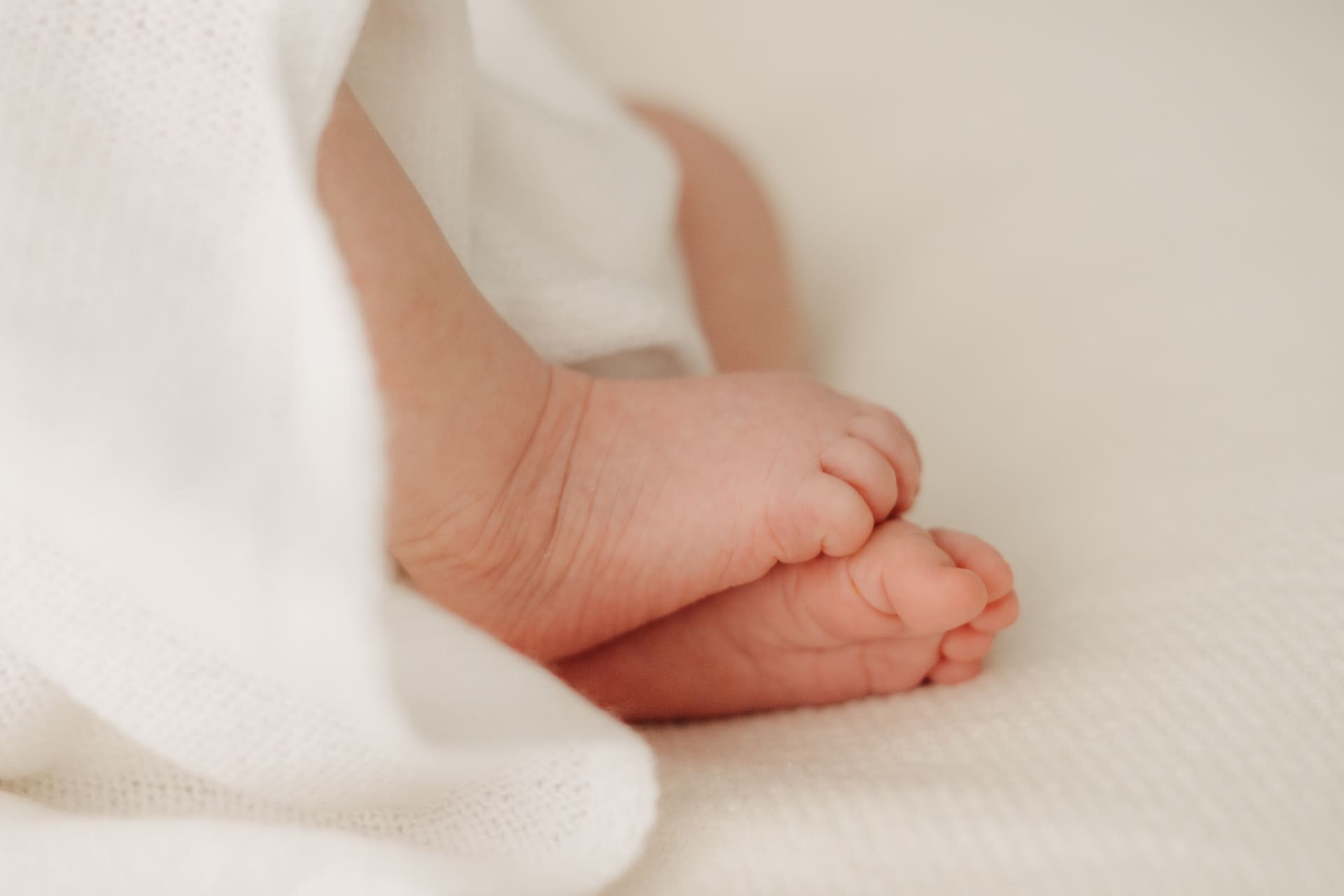 Zarte Babyfüße auf weichem Stoff — Detailaufnahme Newborn-Shooting Bottrop