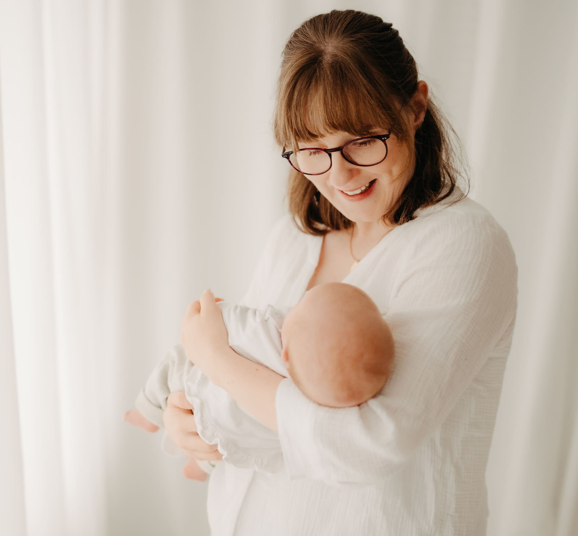 Mama hält ihr Neugeborenes im Arm und strahlt — Newborn-Shooting Bottrop