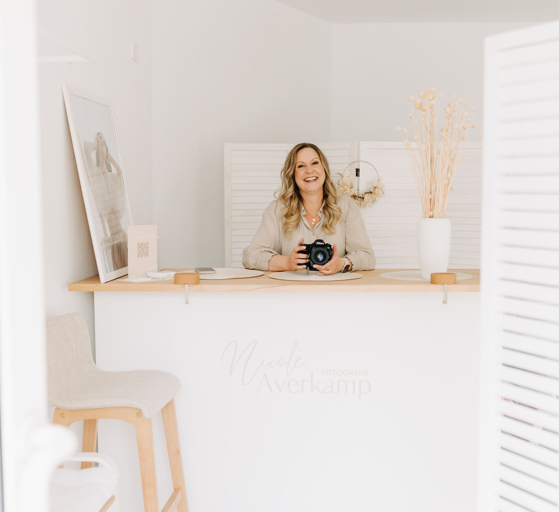 Nicole Averkamp lächelt hinter dem Empfangstresen ihres Studios — herzlich willkommen bei Nicole Averkamp Fotografie in Bottrop