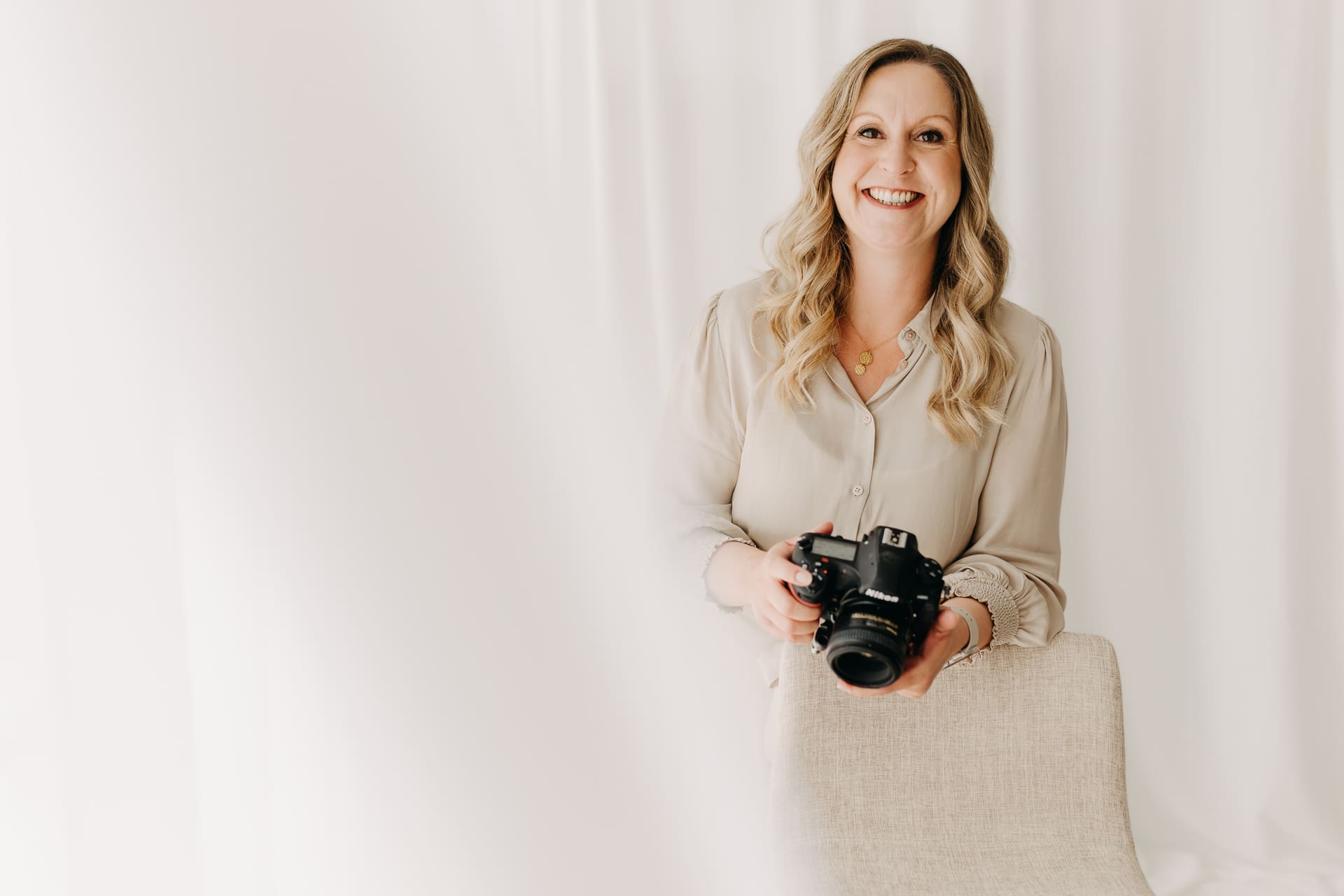 Nicole Averkamp lächelt mit ihrer Kamera direkt in die Kamera — Familienfotografin Bottrop