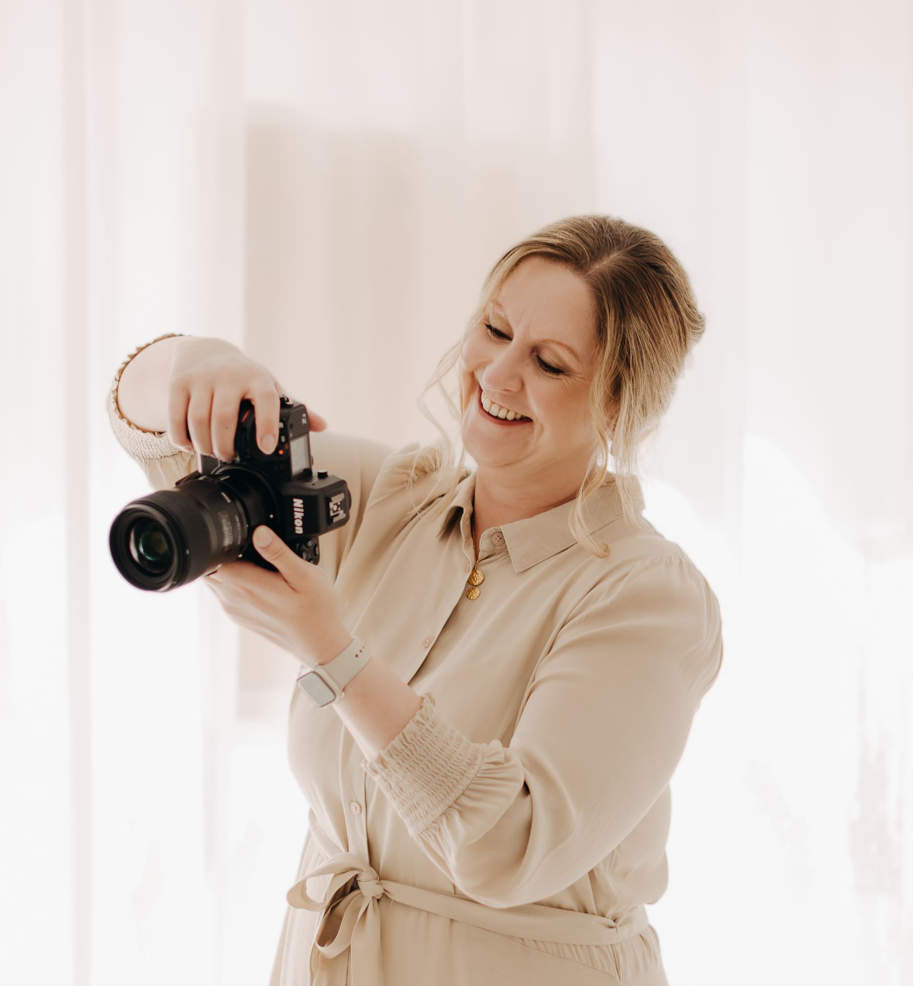 Nicole Averkamp schaut lächelnd auf das Display ihrer Nikon-Kamera — Familienfotografin bei der Arbeit in ihrem Studio in Bottrop