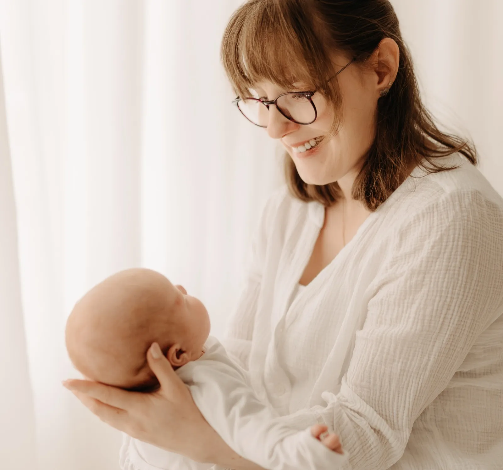 Mama lächelt ihr Baby an, das sie im Arm hält