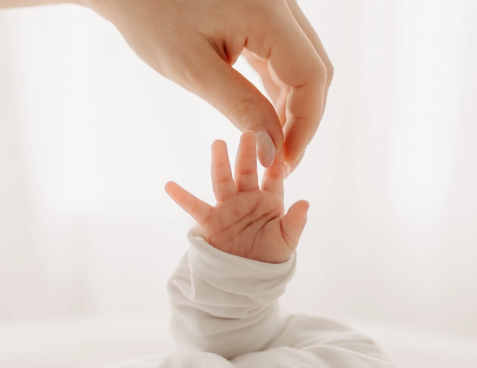 Babyhand greift nach der Hand der Mama
